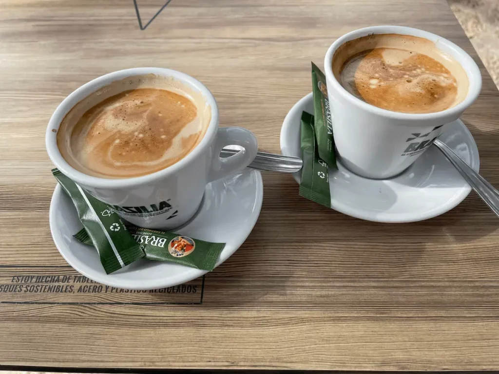 Zwei Tassen Kaffee auf einem Holztisch.