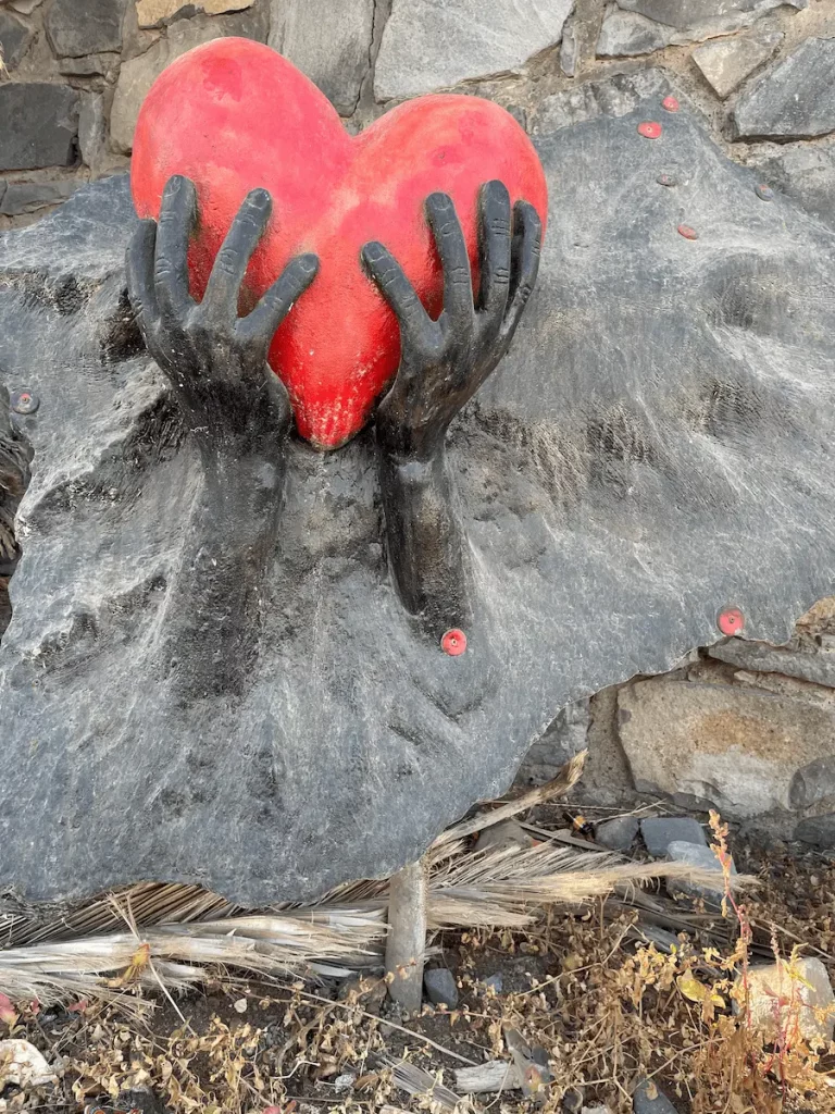 Steinskulptur, wo ein rotes Herz aus einem Stein herausragt.